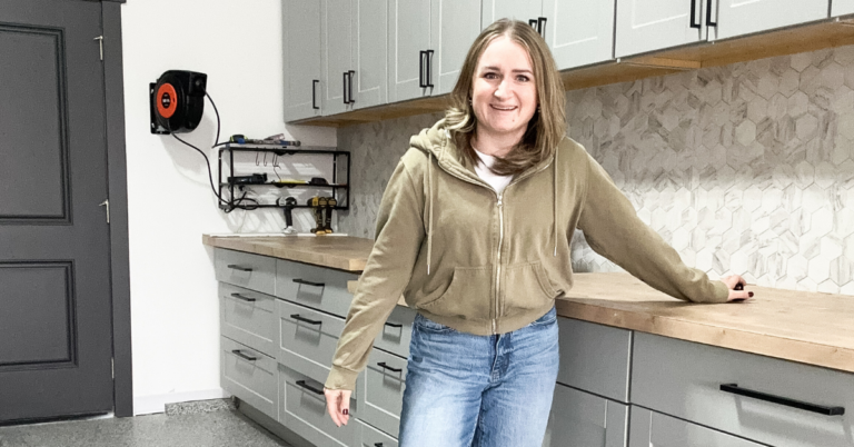 Woman standing by garage workbench with gray cabinets and tan butcher block countertops