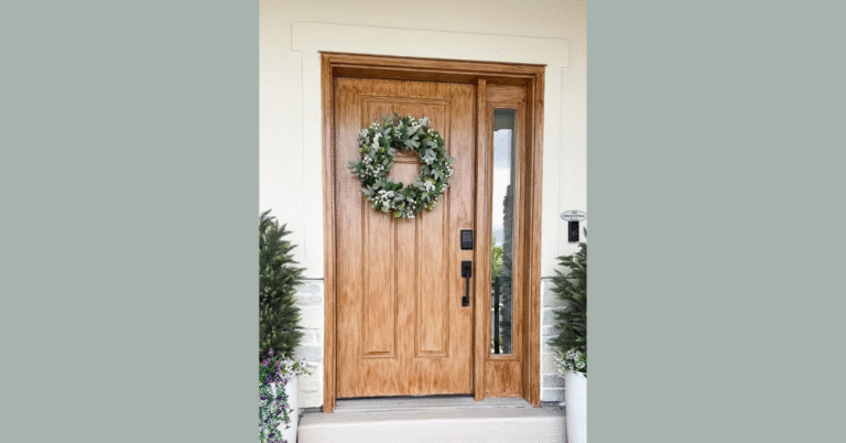 Faux wood door with wreath and greenery around it