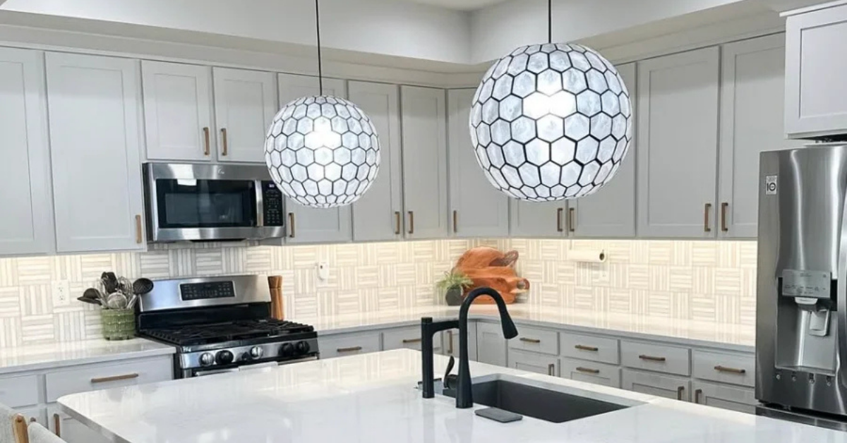 Kitchen with white cabinets, honeycomb-style chandeliers, and white countertops