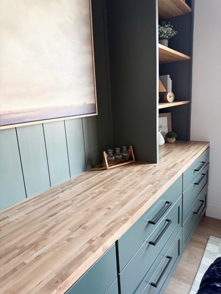 Butcher block counter on dark green built-in cabinets