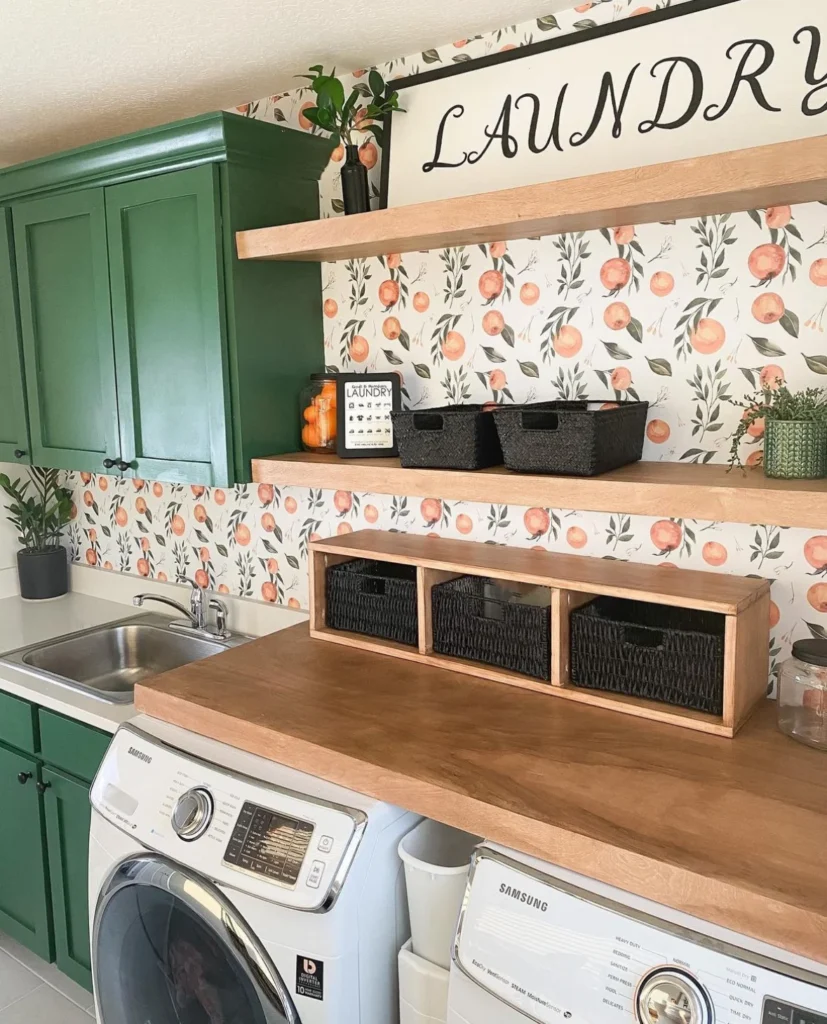Weekend DIY home projects ideas: install light wood floating shelves over washer and dryer. Photo also shows green cabinets and citrus wallpaper behind shelves.