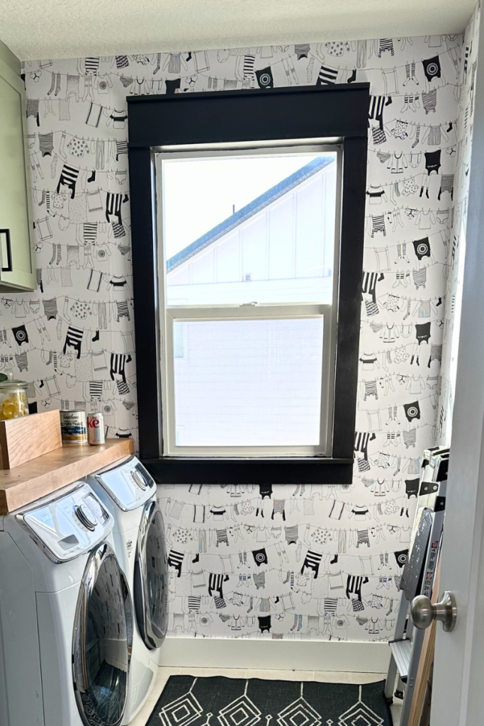 DIY Home Improvements: Adding black trim to a laundry room window surrounded by clothesline wallpaper