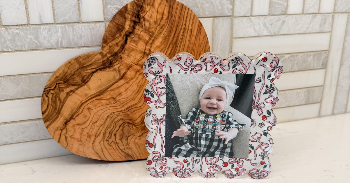 Decoupage picture frame with scalloped edges and cherry/bow print, placed on the kitchen counter in front of a heart-shaped cutting board