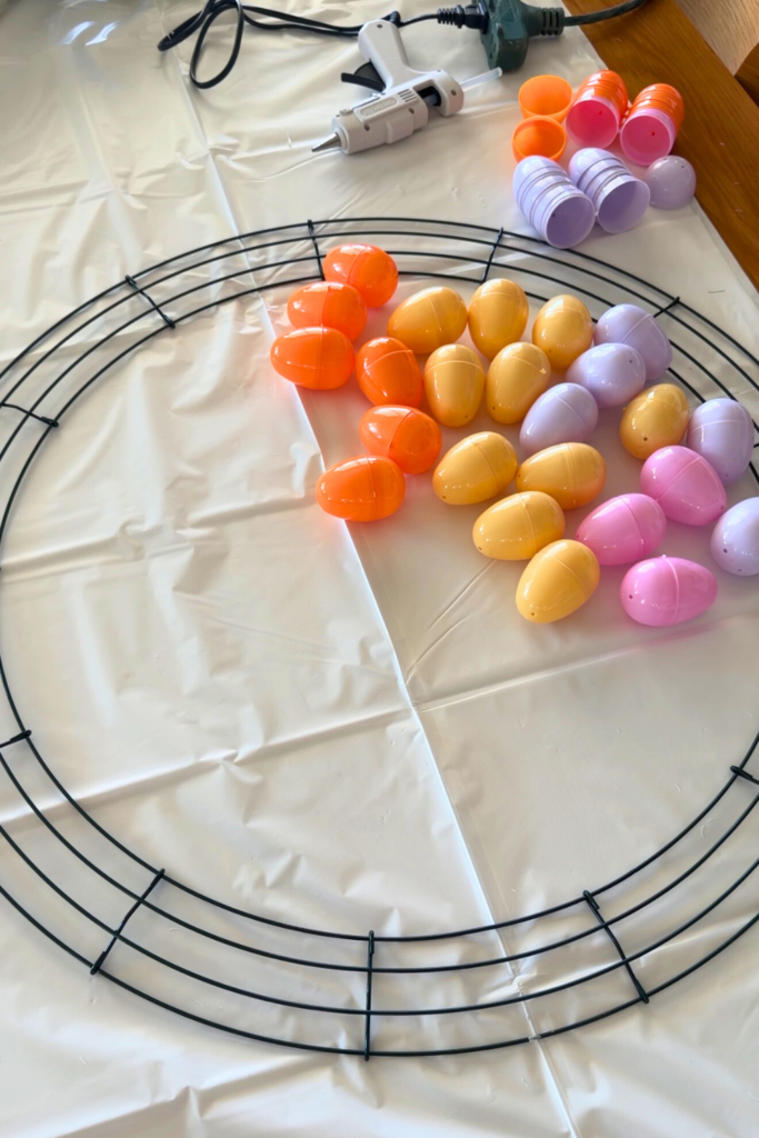 Prepping to make my DIY Easter egg wreath by laying the orange, yellow, pink, and purple eggs next to the circle wire frame