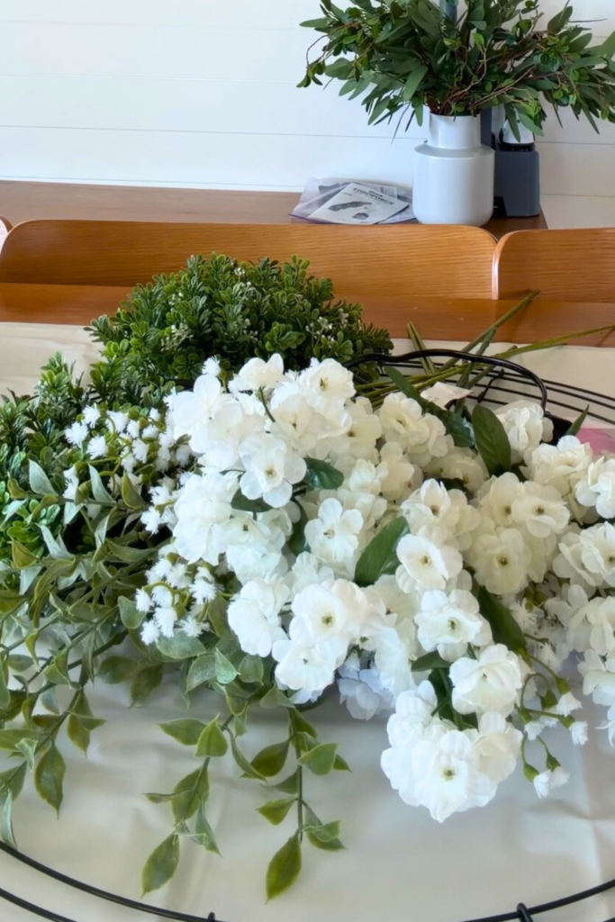 Prepping to make my DIY Easter egg wreath by laying out the greenery: boxwood and eucalyptus stems, and small white flowers