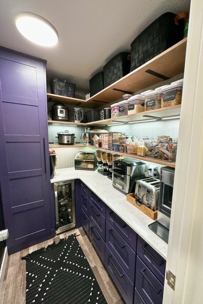 Pantry with open shelving and dark purple cabinets, with black modern drawer pulls