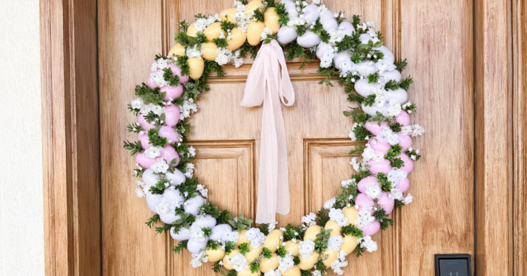 Pink, white, and yellow Easter egg wreath on a wooden front door