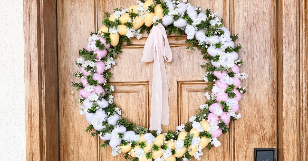 Pink, white, and yellow Easter egg wreath on a wooden front door