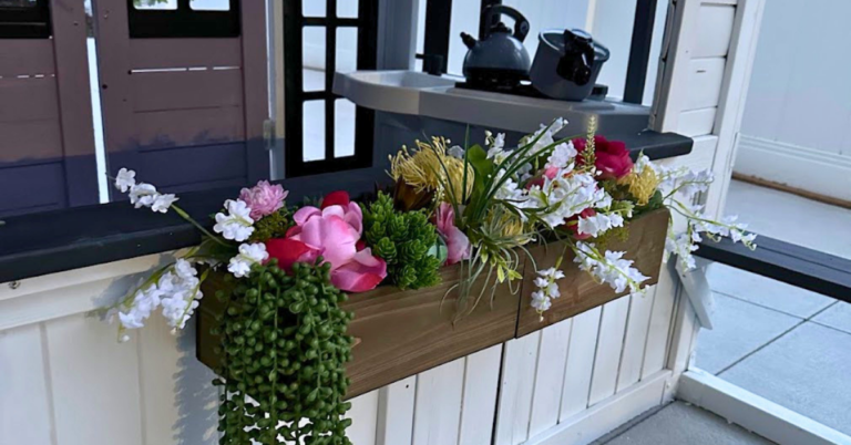 Free backyard ideas: a DIY playhouse with a faux flower box and play kitchen in the background