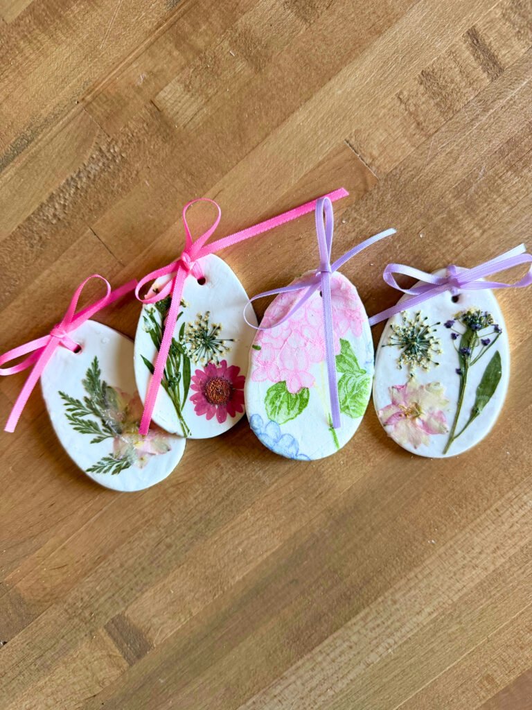 Clay Easter eggs with dried pressed flowers, decoupage napkins, and pink and purple ribbons