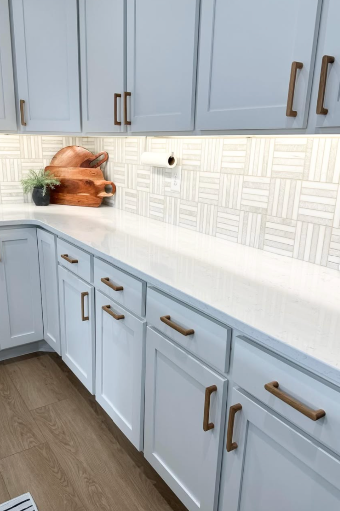 How to choose cabinet hardware example with white cabinets and modern wood handles, plus white counters and white and gray backsplash