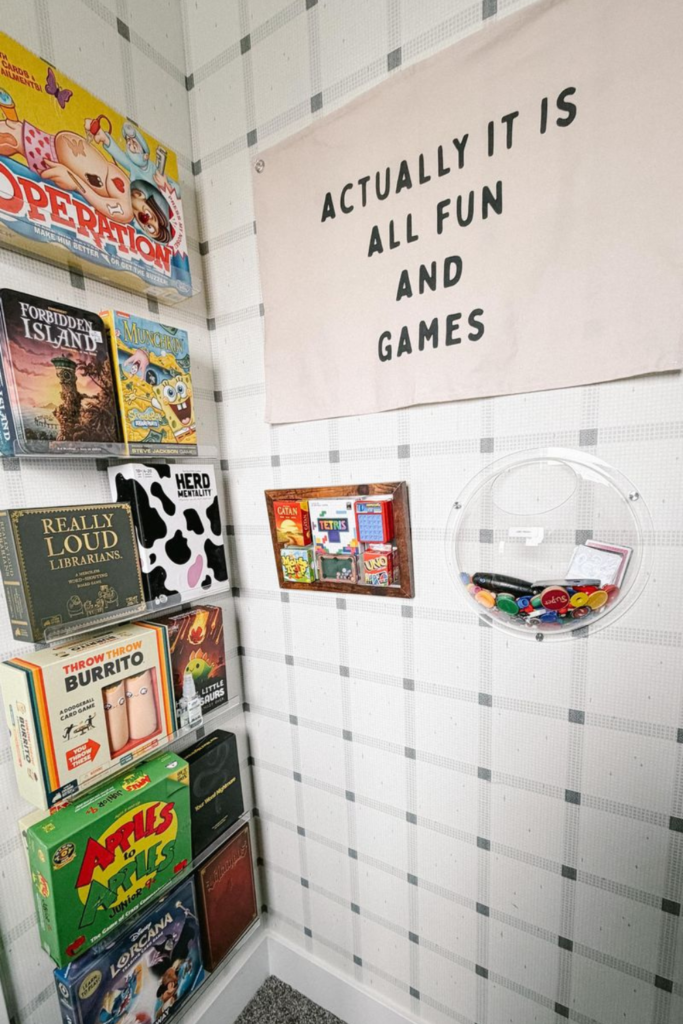 Game room closet with board games sitting on acrylic shelves and a canvas sign that says "actually it is all fun and games"