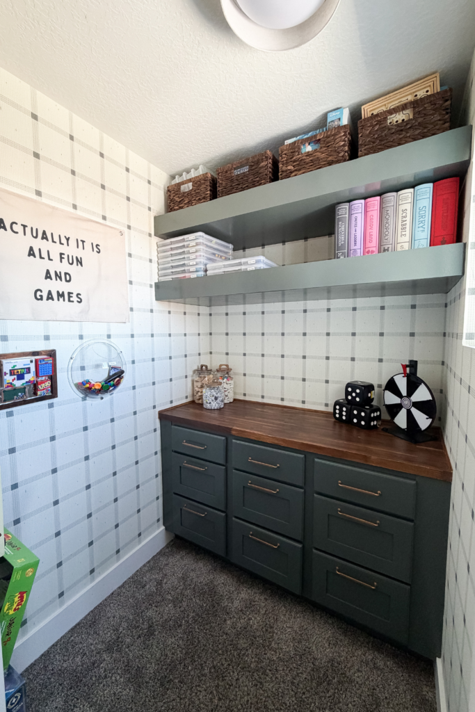 Game Room Closet with gray cabinets and floating shelves, a dark wood butcher block counter top, and game-themed decor