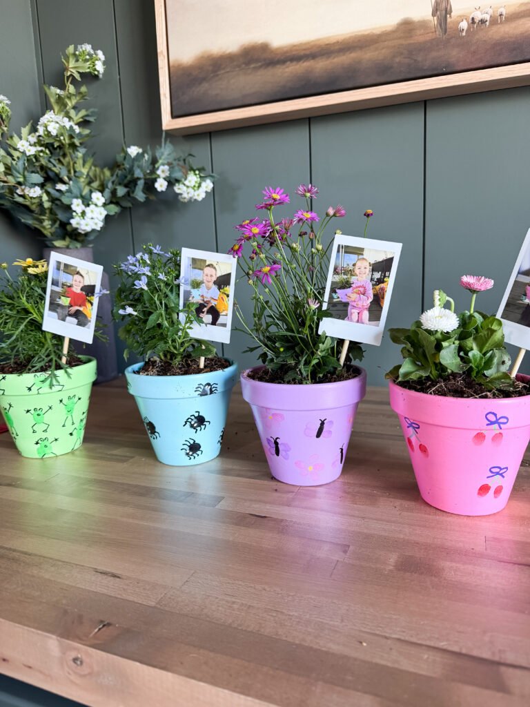 DIY Mother's Day crafts: fingerprint art on painted pots with mini Polaroids attached to sticks in the soil