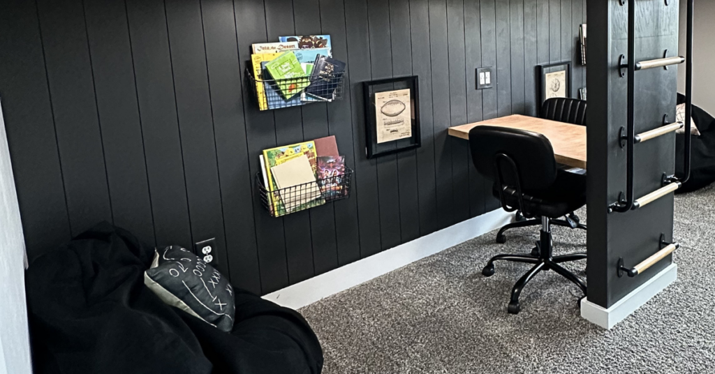 Black shiplap with hanging baskets filled with books, and a desk