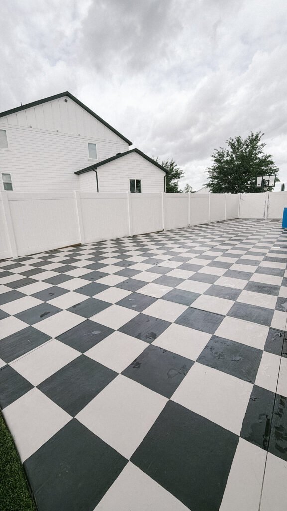 Black and gray checkerboard painted patio with a white vinyl fence