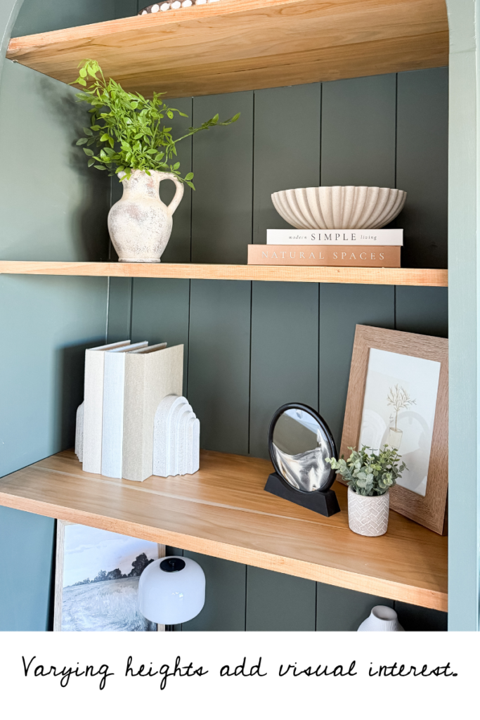 Shelf styling example: Use varying heights of items, including plants, books, bowls, art, and other decorative objects