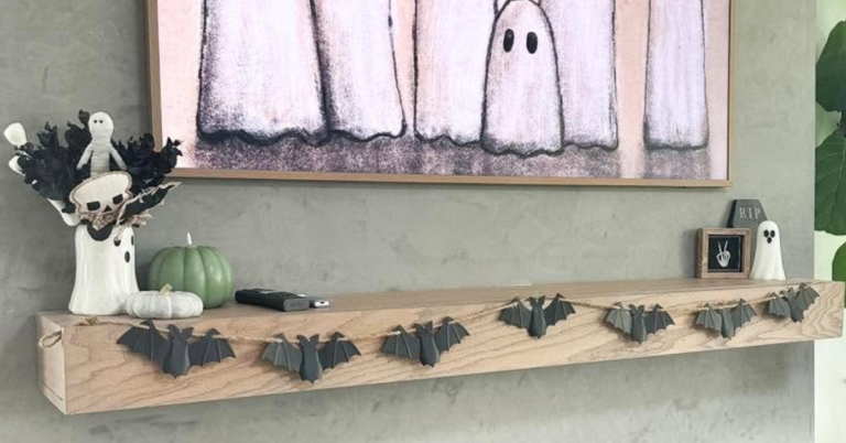 Example of how to style a mantel for every season with a bat garland, ghost art on the tv, and miscellaneous Halloween decorations