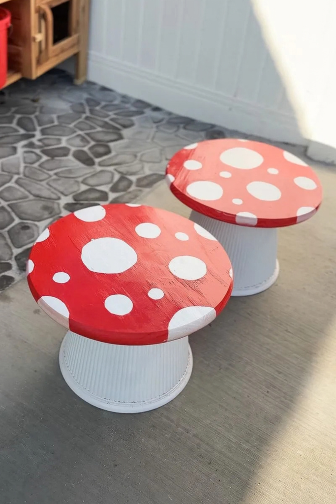 DIY toadstool tables with large white spots against a red background on top, and ribbed white planters acting as the base