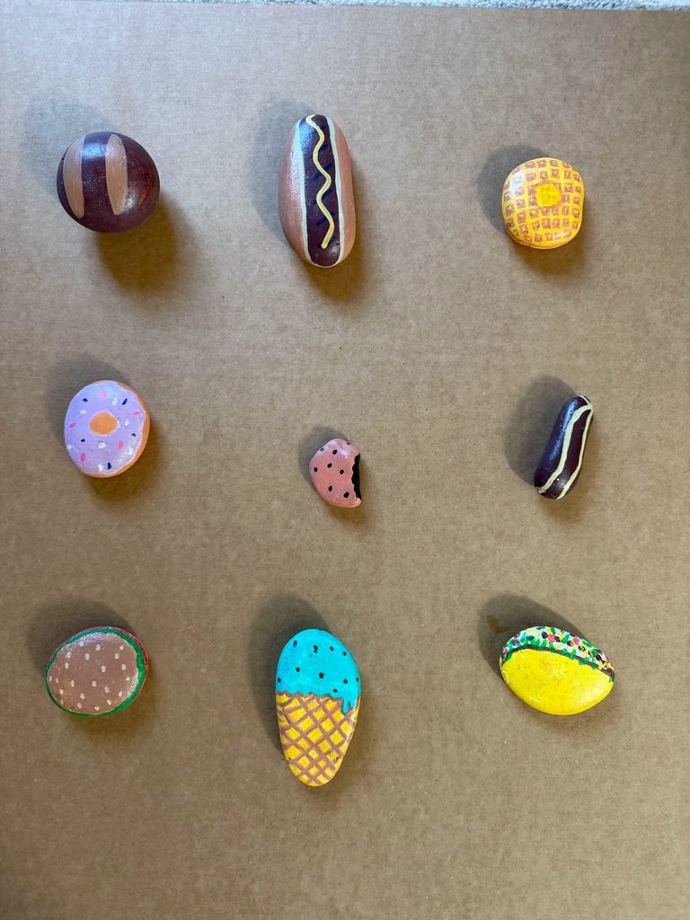 Painted rock food examples including a hot dog, donut, ice cream, taco, and more