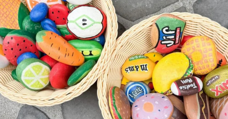 A variety of painted rock food including fruit, vegetables, candy, peanut butter, and a donut