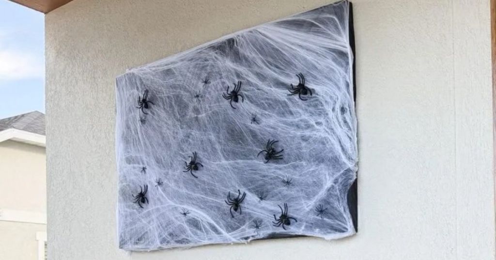 Halloween porch decor idea: a black foam board with spider webs and spiders on it