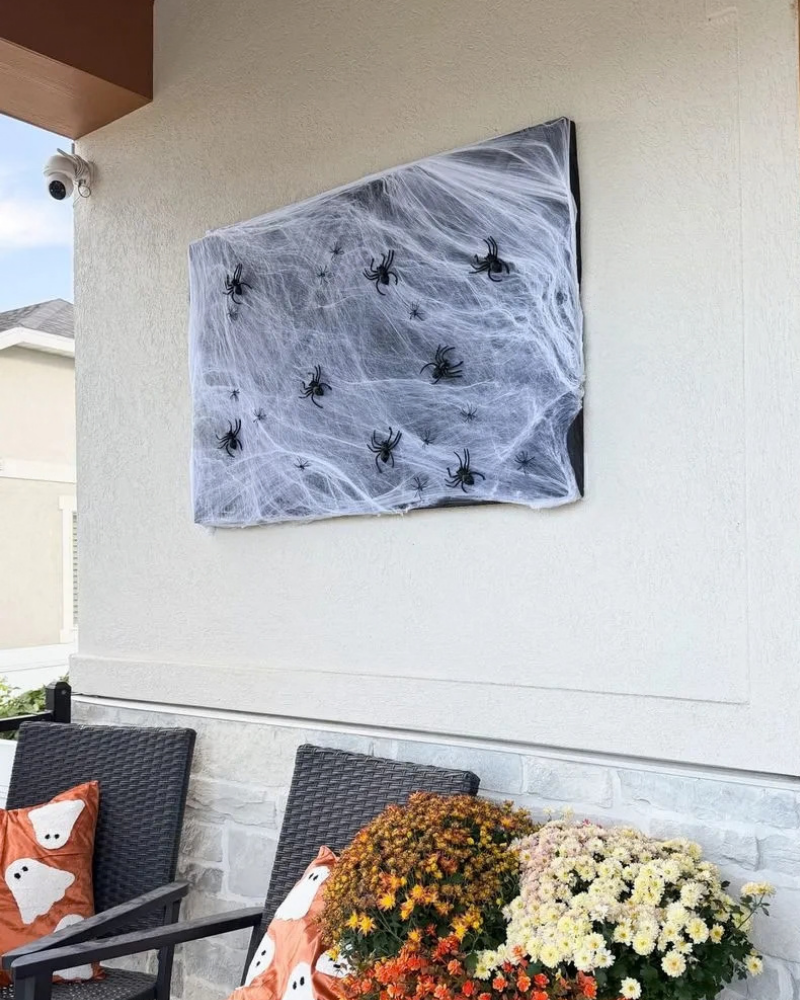 Halloween porch decor idea: a black foam board with spider webs and spiders on it